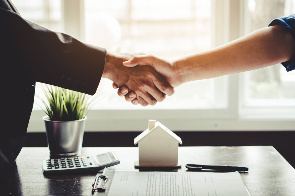 A real estate agent and new homeowner shaking hands after closing a deal.