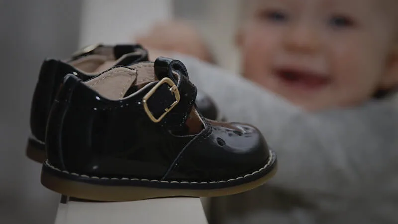 little girl looking at black buckle shoes