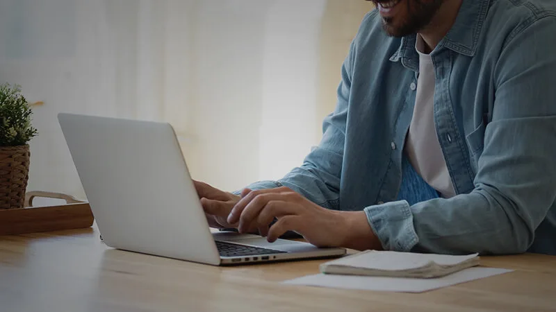 a man types at a laptop