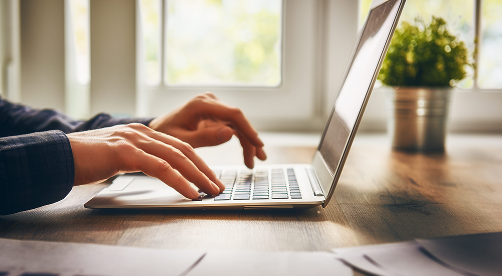 Close up of hands typing on laptop.