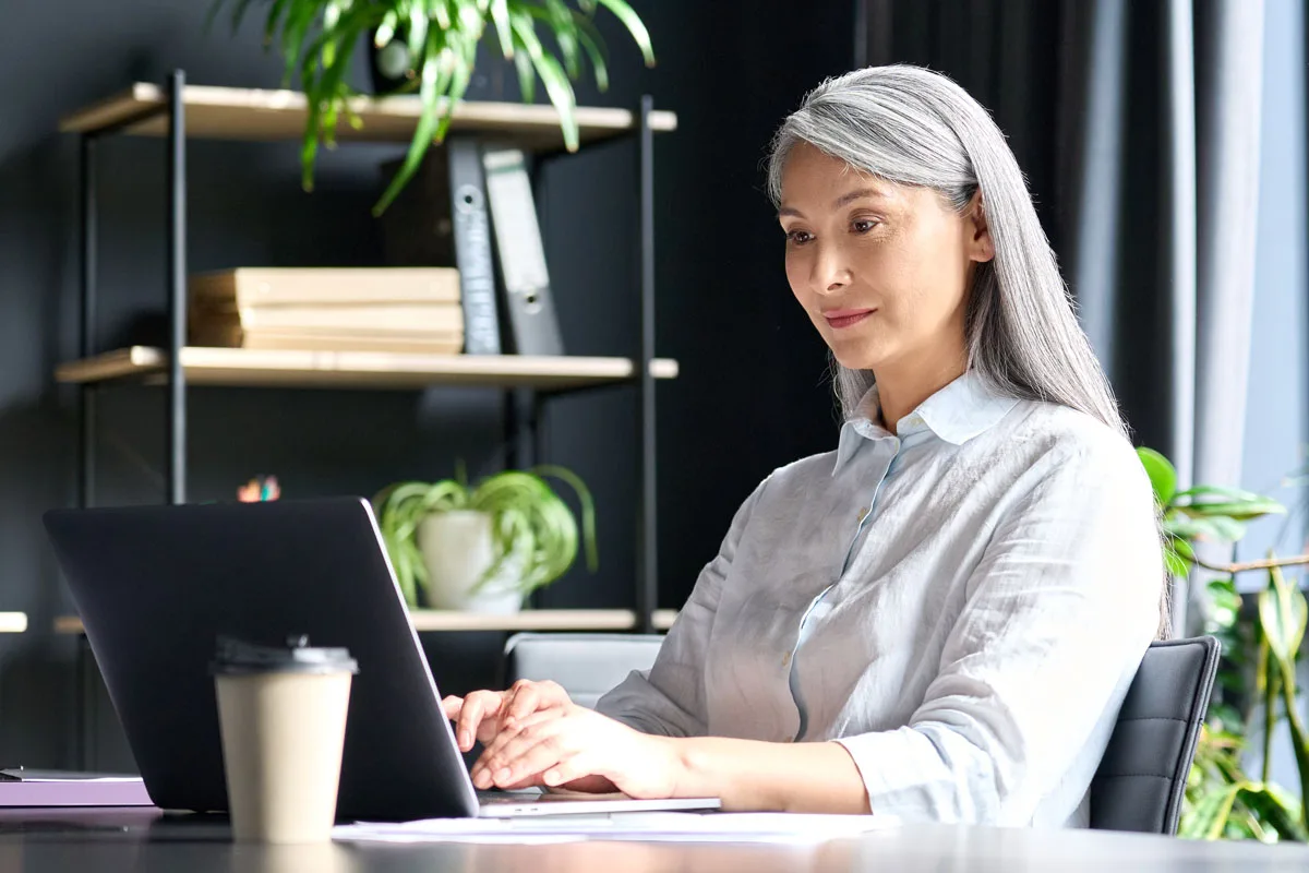 An older woman using a laptop in her office