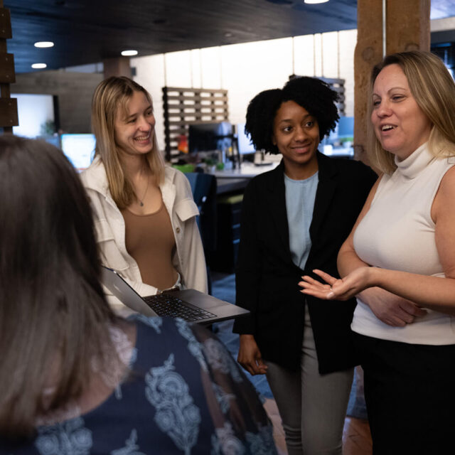 Group of Tower Marketing employees discussing digital marketing strategy around a desk in the Tower Marketing office