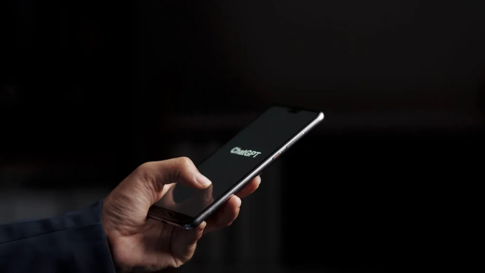 a person holds a phone with ChatGPT on the screen