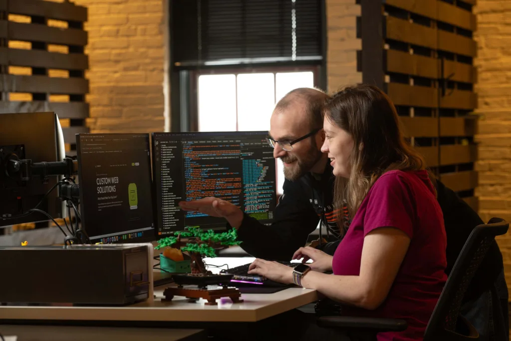 two web developers look at a screen of code to discuss Duda vs WordPress