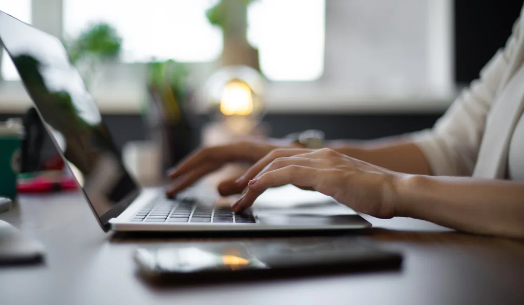 Internet marketing specialist typing on a laptop at their desk.