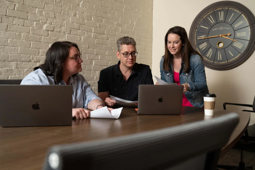 Three employees sit at a table at an engineering marketing agency
