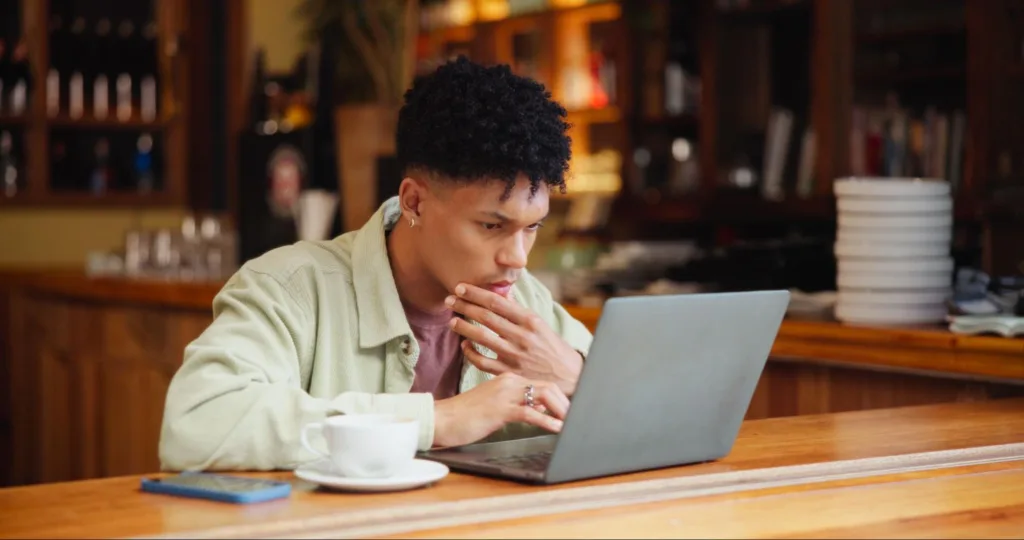 Professional in coffee shop on laptop reading about long-form content and AI