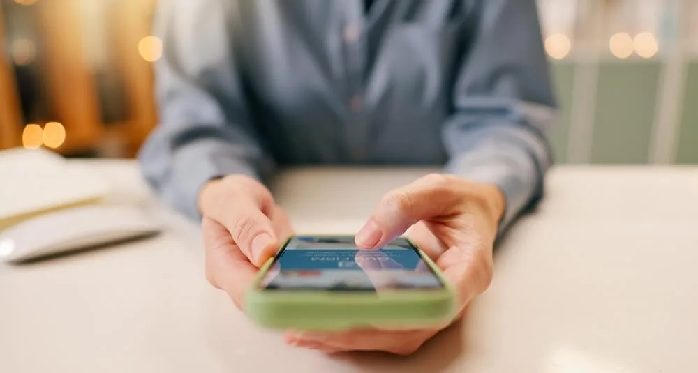 A person scrolls on their phone, looking at Meta ads